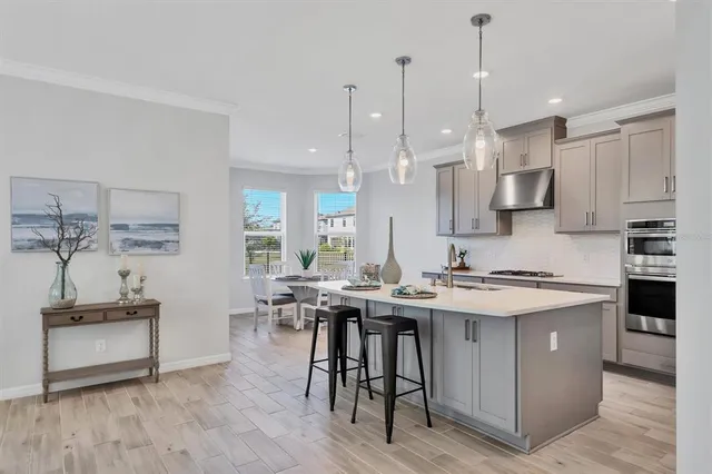 a kitchen with stainless steel appliances kitchen island a table chairs in it and wooden floors