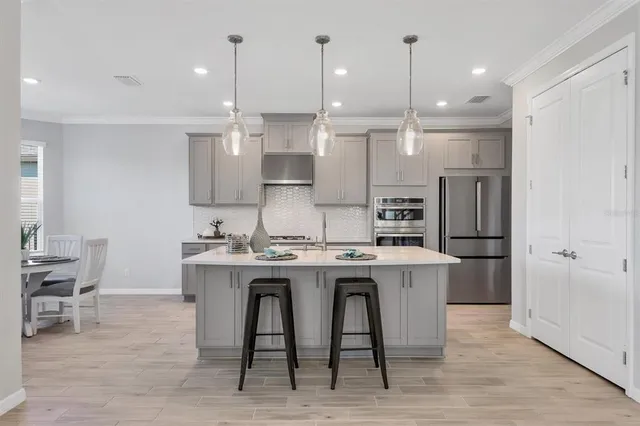 a kitchen with kitchen island a dining table chairs sink and cabinets