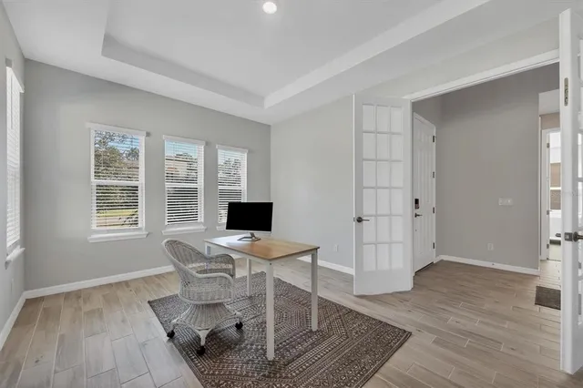 a work room with furniture a large window and wooden floor