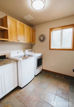 a utility room with a sink a cabinetry and a window
