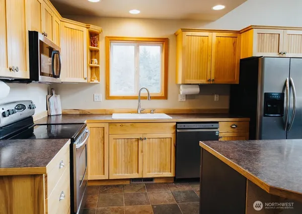 a kitchen with stainless steel appliances granite countertop a sink stove refrigerator and cabinets
