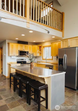 a kitchen with stainless steel appliances kitchen island granite countertop a table chairs and a refrigerator