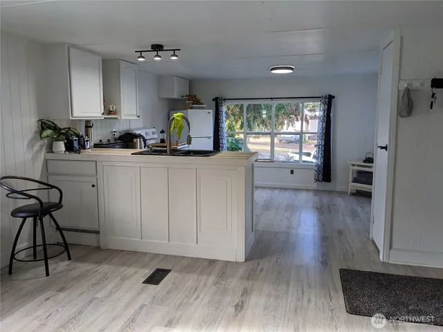 a kitchen with stainless steel appliances granite countertop a stove a refrigerator a sink a dining table and chairs with wooden floor