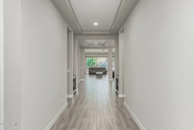 a view of a hallway with wooden floor and chandelier