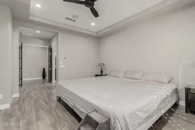 a bed sitting in a bedroom next to a window with a balcony and dresser