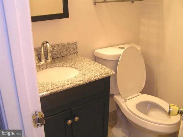 a bathroom with a granite countertop toilet sink and mirror