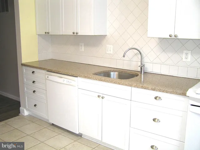 a kitchen with granite countertop white cabinets and a sink