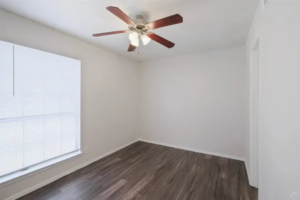 an empty room with wooden floor and ceiling fan