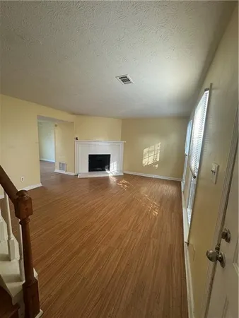 a view of empty room with wooden floor and fireplace