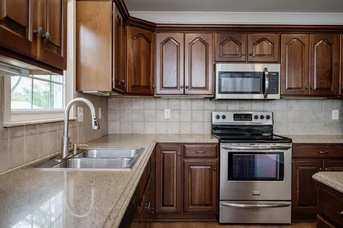 a kitchen with stainless steel appliances granite countertop a stove a microwave and a sink