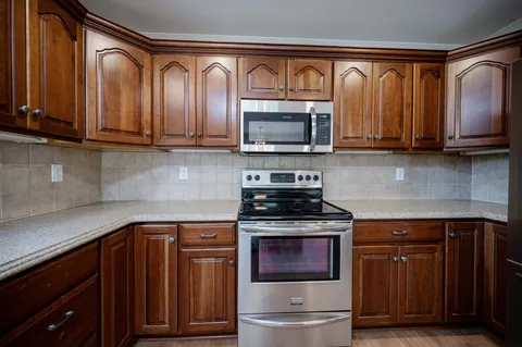 a kitchen with stainless steel appliances granite countertop a stove microwave and cabinets