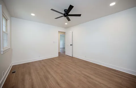 an empty room with wooden floor and ceiling fan