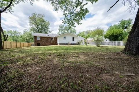 a view of a house with a yard and large trees
