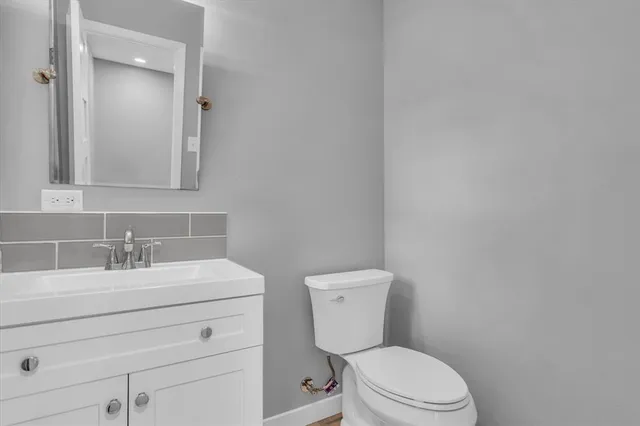 a bathroom with a toilet sink vanity and mirror