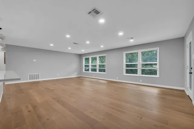 a view of an empty room with wooden floor and windows