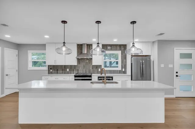 a large kitchen with kitchen island stainless steel appliances a stove a center island and chairs