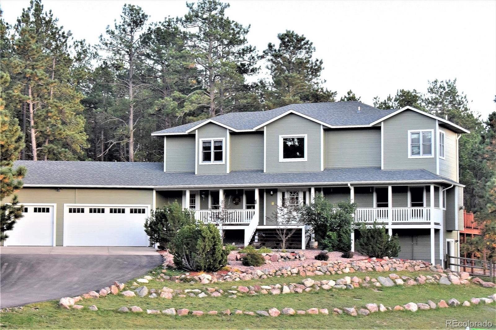 2355 Bricker Road Monument, CO 80132 - Photo 1 of 35 a view of a white house with large windows and a yard with plants and large tree