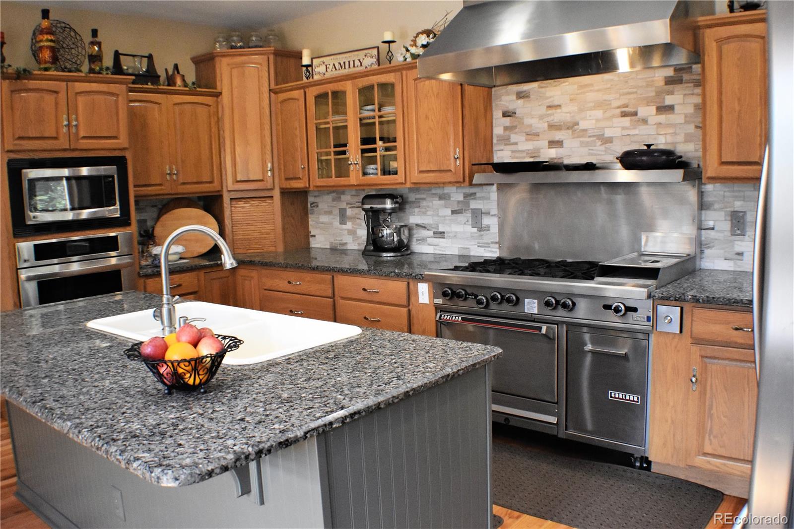 2355 Bricker Road Monument, CO 80132 - Photo 4 of 35 a kitchen with stainless steel appliances granite countertop a stove a sink dishwasher and cabinets with wooden floor