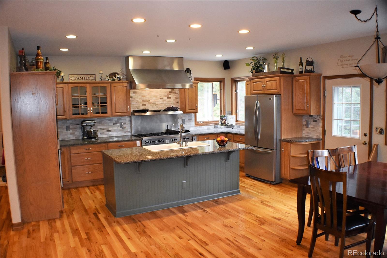 2355 Bricker Road Monument, CO 80132 - Photo 5 of 35 a kitchen with stainless steel appliances granite countertop a refrigerator a stove a sink dishwasher and a dining table with wooden floor