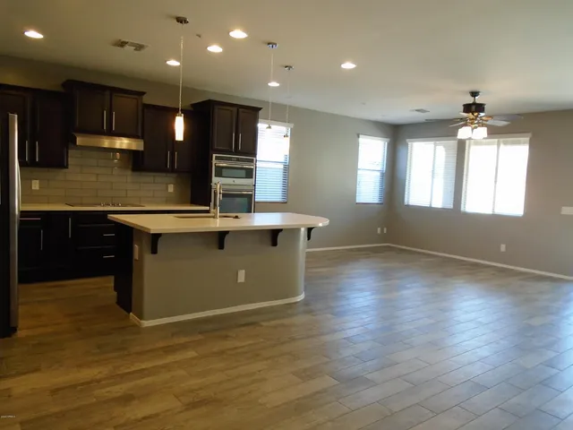 a large kitchen with stainless steel appliances kitchen island a large counter top and a refrigerator