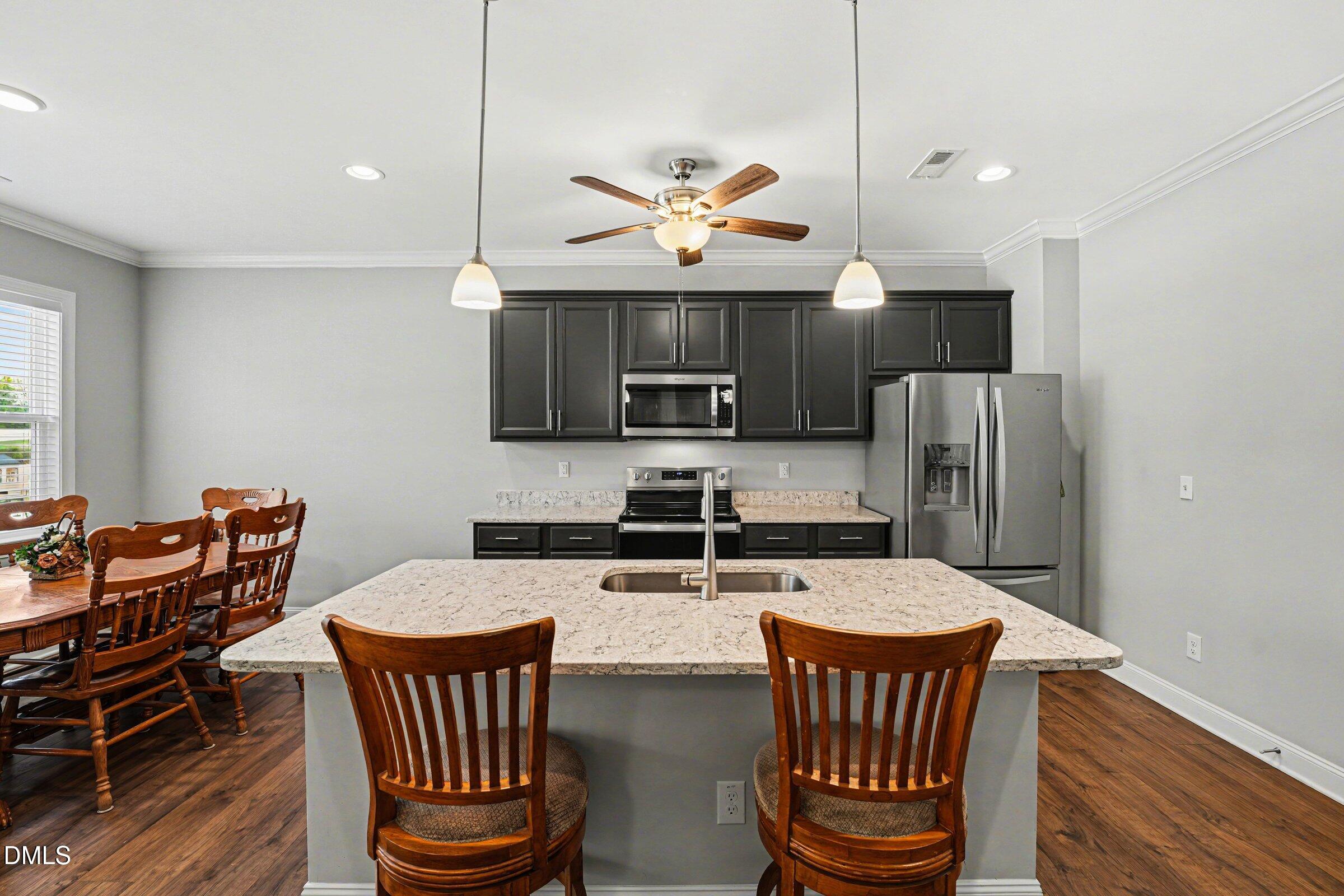 130 Aylebury Ridge Zebulon, NC 27597 - Photo 14 of 41 a kitchen with stainless steel appliances kitchen island granite countertop a dining table chairs and a refrigerator