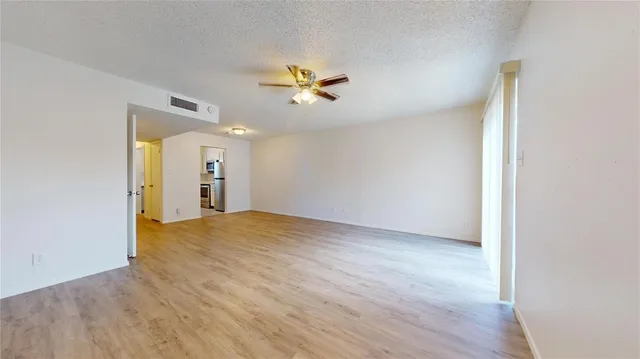a view of a livingroom with a chandelier fan and wooden floor