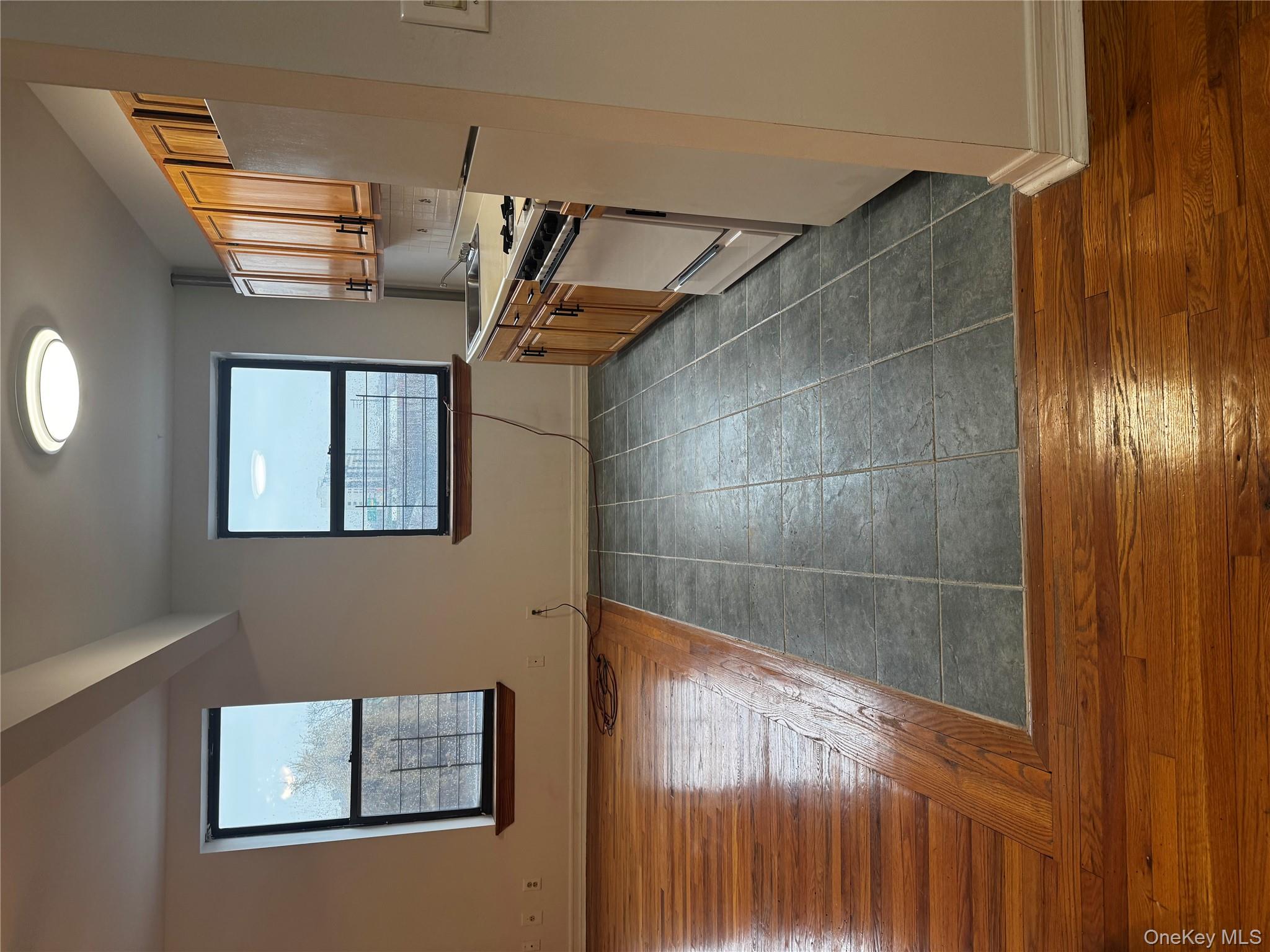 875 Longfellow Avenue, Unit 4C Bronx, NY 10474 - Photo 2 of 4 Kitchen with dark wood-style floors, black refrigerator, range, and brown cabinets