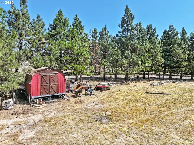 a view of a wooden house with a yard and sitting area