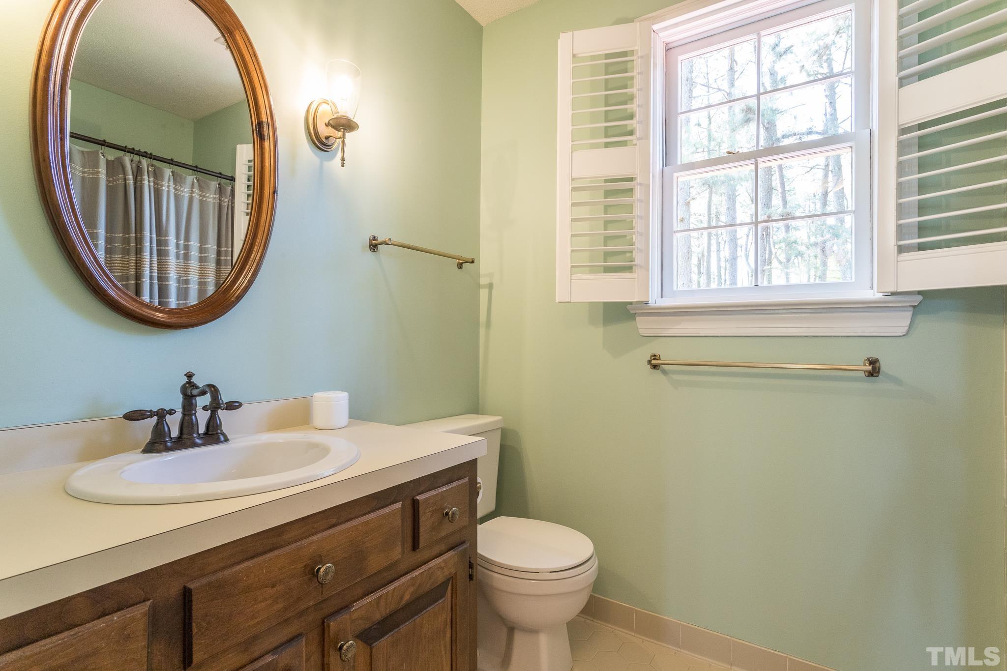 2700 Farnborough Road Raleigh, NC 27613 - Photo 27 of 36 a bathroom with a sink a mirror a toilet and a window
