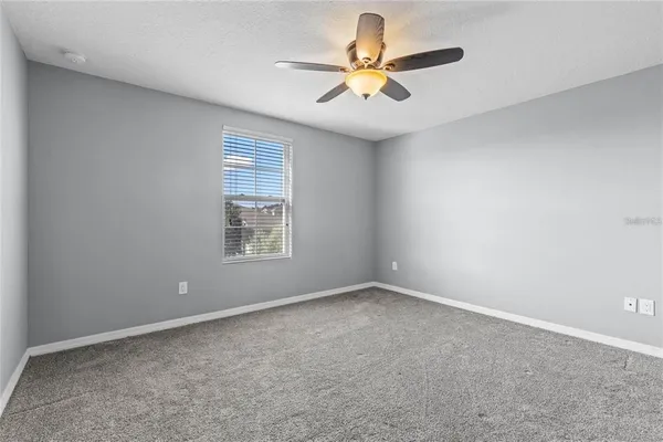 an empty room with a window and a ceiling fan