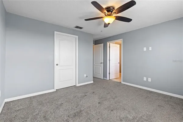 an empty room with closet and a chandelier fan