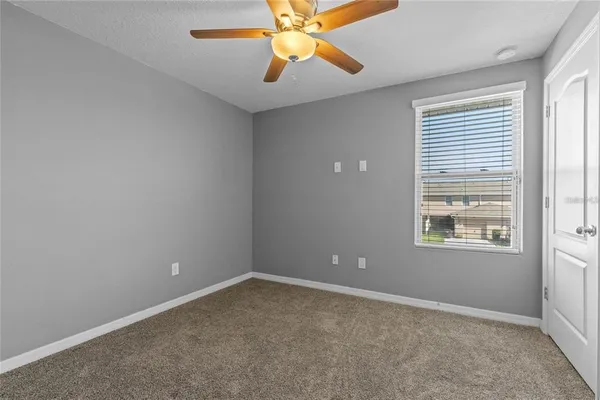 an empty room with a window and a fan