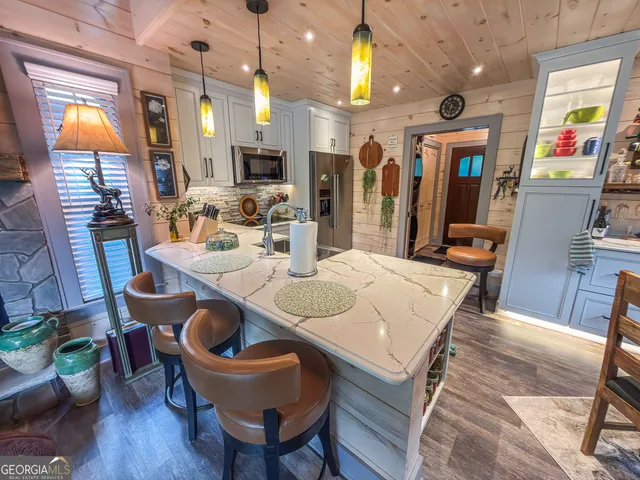 a kitchen with stainless steel appliances a stove a sink dishwasher a refrigerator and a microwave oven with wooden floor