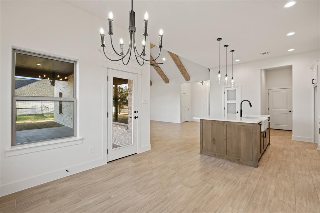 7004 Rnch Vw Place Springtown, TX 76082 - Photo 8 of 25 Open-concept space featuring wood-finish flooring, a kitchen island with a farmhouse sink, and vaulted ceilings with exposed beams