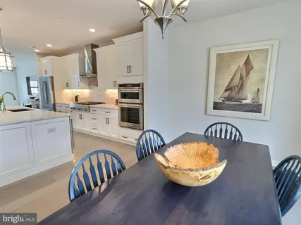 a kitchen with stainless steel appliances kitchen island granite countertop a stove a sink a dining table and chairs
