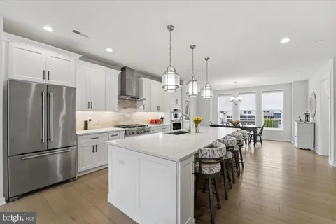 a kitchen with stainless steel appliances granite countertop a refrigerator a sink dishwasher a stove and a refrigerator with wooden floor