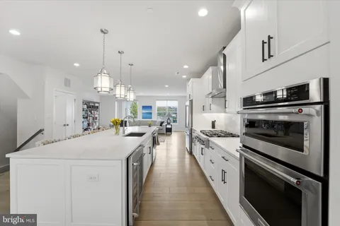 a large kitchen with kitchen island white cabinets and stainless steel appliances