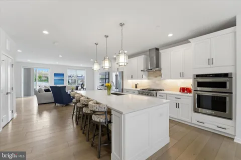 a large white kitchen with lots of counter space a sink appliances and cabinets