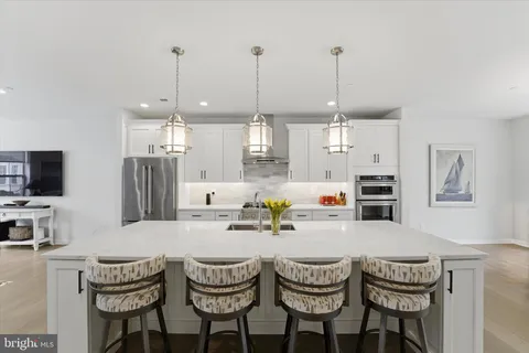 a kitchen with stainless steel appliances a dining table chairs and white cabinets