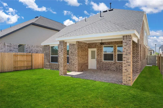 a view of a house with brick walls and a yard with a large tree