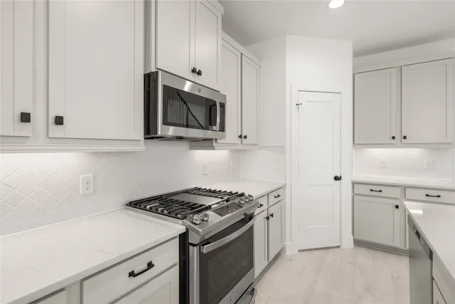 a kitchen with white cabinets and appliances