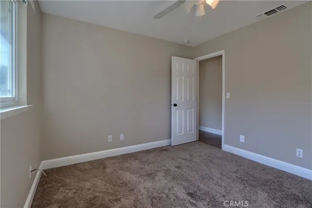 an empty room with windows and fan