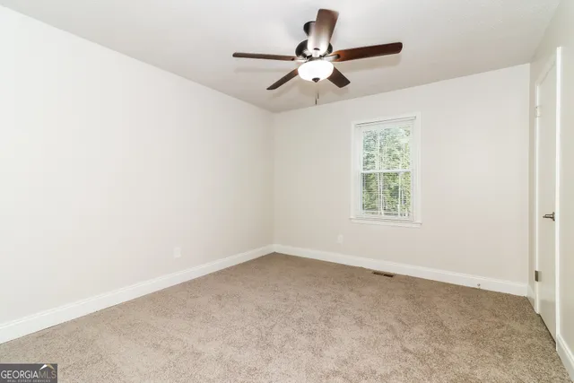 an empty room with a window and a fan