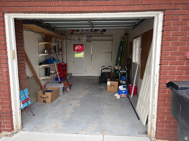 2313 150 East Bountiful, UT 84010 - Photo 39 of 39 Brick exterior garage featuring a concrete floor, built-in shelving, and a rear door with an exterior window