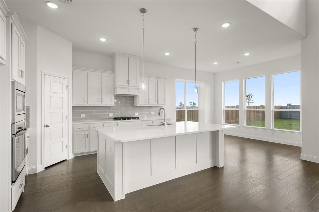 764 Texas Thistle Road Waxahachie, TX 75165 - Photo 4 of 30 a kitchen with stainless steel appliances granite countertop a refrigerator a sink dishwasher a stove and white cabinets with wooden floor