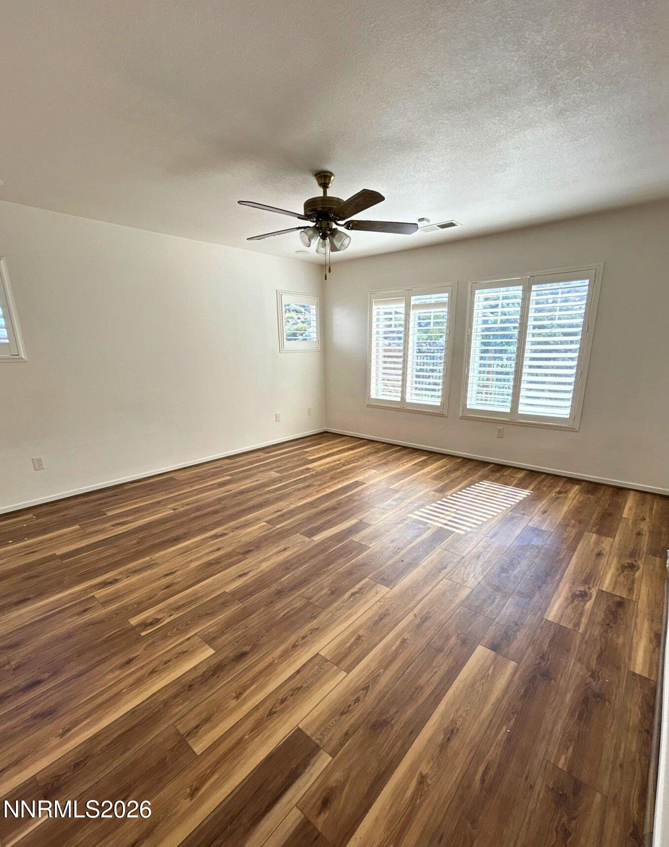 7614 Corso Street Reno, NV 89506 - Photo 9 of 15 an empty room with wooden floor ceiling fan and windows