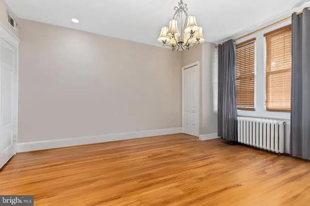 an empty room with wooden floor and mirror