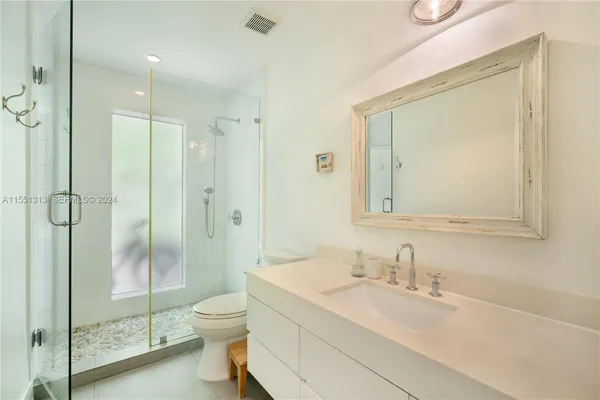 a bathroom with a shower sink vanity mirror and toilet