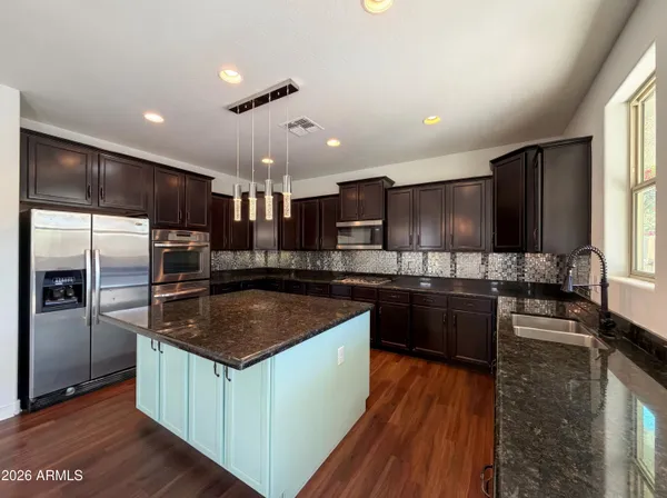 a kitchen with stainless steel appliances granite countertop a sink a stove a refrigerator and cabinets
