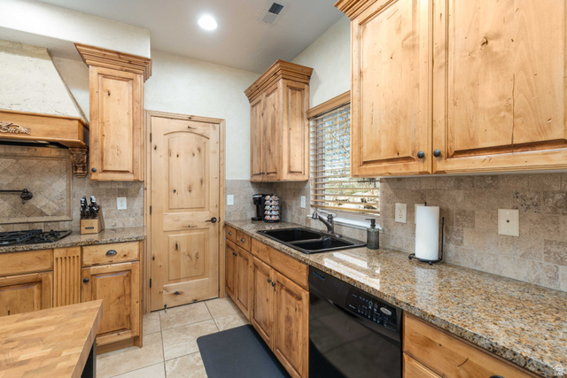 5168 Fairview Loop, Unit C604 Eden, UT 84310 - Photo 5 of 53 Kitchen featuring black appliances, light stone counters, light tile patterned floors, and decorative backsplash